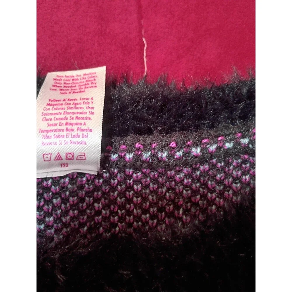 This is a Justice girls' black fuzzy eyelash sweater featuring pink and blue...